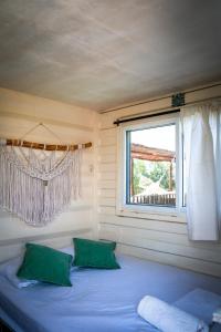 a bed with two green pillows in a room with a window at Tribu Hostal in El Paredón Buena Vista