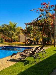 a couple of benches sitting next to a swimming pool at Chalés Araras do Vale in Colinas Do Sul