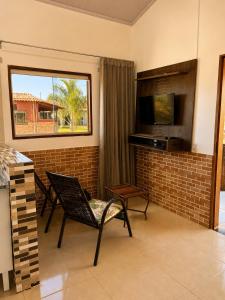 a living room with two chairs and a television at Chalés Araras do Vale in Colinas Do Sul