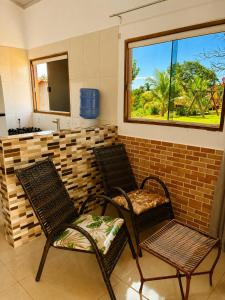 two chairs and a sink in a room with a window at Chalés Araras do Vale in Colinas Do Sul