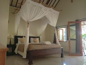 a bedroom with a canopy bed with white curtains at Batu Ampar Menjangan in Banyuwedang +56 photos