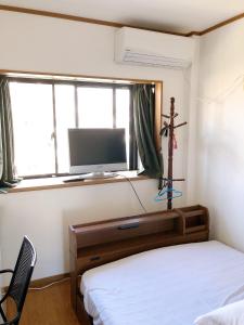 a bedroom with a bed and a tv and a cross on a window at HOSTEL198 Private Room of Third floorーVacation STAY68050v in Osaka