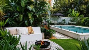 a garden with a fire pit next to a pool at Moso House Pearl Beach in Pearl Beach