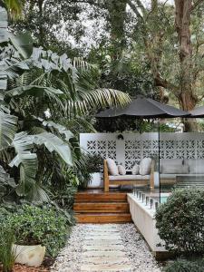 a garden with a bench and an umbrella at Moso House Pearl Beach in Pearl Beach