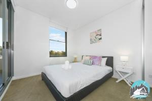 a white bedroom with a bed and a window at Asquith 2BR Apt Secure Underground Parking in Asquith