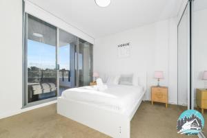 a white bedroom with a white bed and a large window at Asquith 2BR Apt Secure Underground Parking in Asquith