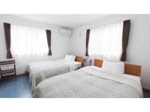 two beds in a room with windows at TEA TREES - Vacation STAY 86519v in Tateyama