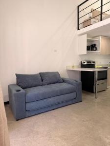 a blue couch in a living room with a kitchen at Apartamentos Aledu in Brasilito +2 photos