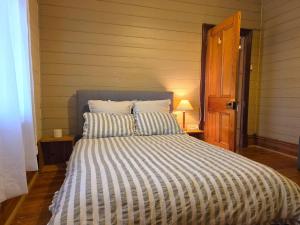 a bed with a striped comforter in a room at Cosy Cottage in Port Broughton