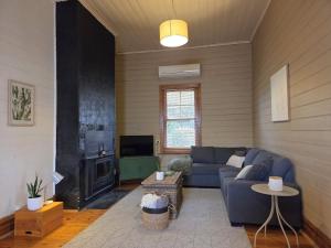 a living room with a blue couch and a tv at Cosy Cottage in Port Broughton