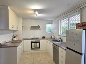 a kitchen with white cabinets and a white refrigerator at Cosy Cottage in Port Broughton +9 photos