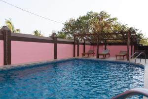 a swimming pool with two chairs and a pink wall at Westwood Residence Goa - The Boutique Hotel in Mapusa