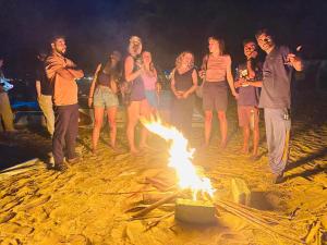 a group of people standing around a bonfire on the beach at Saha surf camp lesson booking only in Pottuvil
