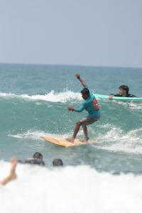 a man riding a wave on a surfboard on the beach at Saha surf camp lesson booking only in Pottuvil