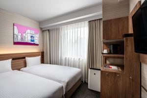 a hotel room with two beds and a flat screen tv at Noku Osaka in Osaka