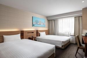 a hotel room with two beds and a desk at Noku Osaka in Osaka