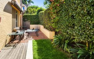 a patio with a table and a bench next to a hedge at Ocean Tracks in Kiama