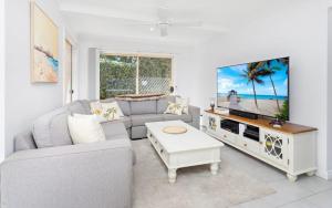 a living room with a couch and a tv at Ocean Tracks in Kiama