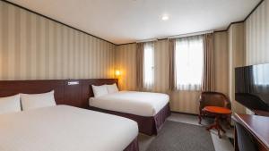 a hotel room with two beds and a television at TsukubaNoYu Urban Hotel in Tsukuba