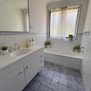 a white bathroom with a sink and a tub and a mirror at The Nest in Bidwill