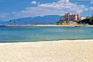 a beach with buildings and palm trees and the ocean at 海しずく Slow in Amakusa