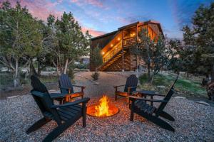 three chairs around a fire pit in front of a cabin at Painted Cliffs-Hot Tub, Amazing Views Between Zion and Bryce in Orderville