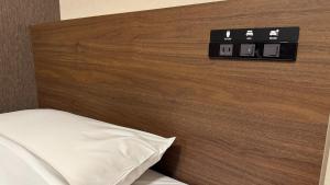 a bedroom with a wooden headboard with a white pillow at Hotel Excel Okayama in Okayama