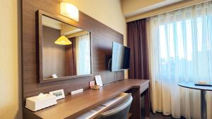 a hotel room with a desk with a television and a window at Hotel Excel Okayama in Okayama