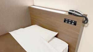 a room with a bed with a phone on the wall at Hotel Excel Okayama in Okayama