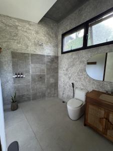 a bathroom with a toilet and a sink and a mirror at Makai Lombok in Selong Belanak