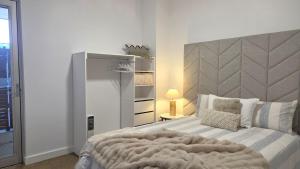 a bedroom with a large bed with a gray headboard at Beach & Bubbles in Port Moonta