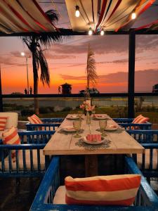 a wooden table with chairs and a sunset in the background at Club Colonial Hotel in Huanchaco