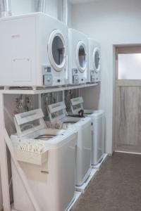 a laundry room with white washing machines and mirrors at guest house ALO in Miyako-jima