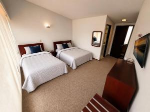 a hotel room with two beds and a mirror at D'Acosta Hotel Belencito in Nobsa