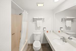 a white bathroom with a toilet and a sink at Vista Inn in Vista