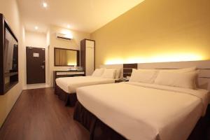 a hotel room with two beds and a mirror at Skytree Hotel in Kuantan