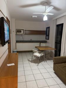 a living room with a table and a tv and a couch at Flat Beira Mar Caraguatatuba in Caraguatatuba