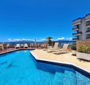 a swimming pool with a view of the ocean at Flat Beira Mar Caraguatatuba in Caraguatatuba
