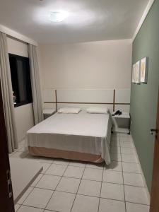 a bedroom with a bed and a tiled floor at Flat Beira Mar Caraguatatuba in Caraguatatuba +3 photos