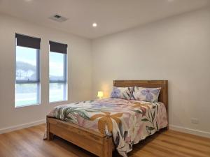 a bedroom with a bed and two windows at Belless at Moonta Bay in Port Moonta