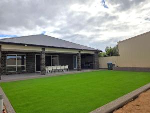 a house with a green lawn in front of it at Belless at Moonta Bay in Port Moonta
