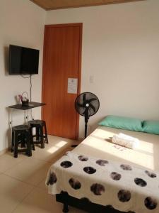 a bedroom with a bed and a table and a television at Quarto 8km Aeroporto MCZ in Maceió +3 photos