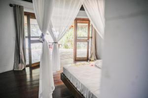 a bedroom with a bed with white curtains and a window at Black Pearl Resort in Espiritu Santo +59 photos