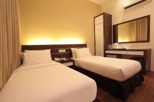 a hotel room with two beds and a mirror at Skytree Hotel in Kuantan