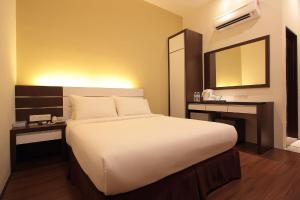 a bedroom with a large white bed and a mirror at Skytree Hotel in Kuantan