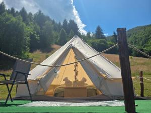 a white tent with a table and a chair at Camping Inima Retezatului in Nucşoara +12 photos