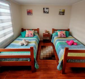 two beds in a room with two chairs at Julieta House in Puerto Natales