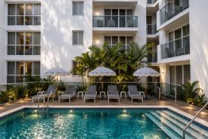 a swimming pool with chairs and umbrellas next to a building at Habitat Residence in Miami