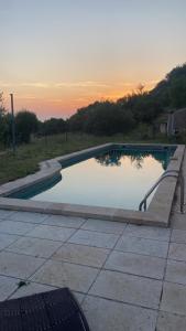 a swimming pool with a bench and the sunset at Maison des lavandes in Apt