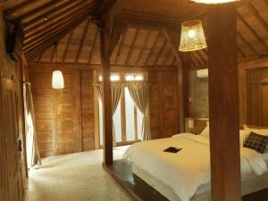 a bedroom with a bed in a wooden cabin at Joglo Villa with Private Pool in Pesanggaran